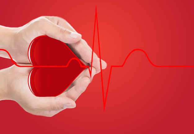 Cuore rosso con coperchio a mano e cardiografo normale su sfondo rosso