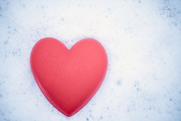 Cuore rosso con gocce d'acqua sulla neve