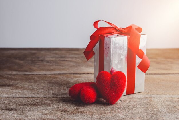 Cuore rosso e contenitore di regalo su un fondo di legno