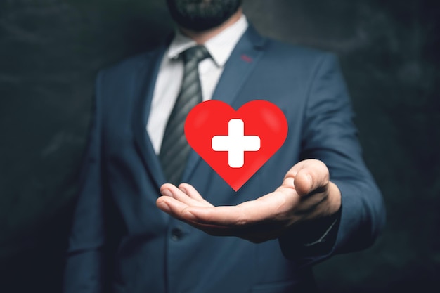 Cuore rosso e croce Concetto di medicina Uomo che tiene in mano