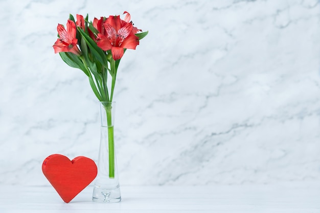 Cuore rosso e fiori in vaso su bianco