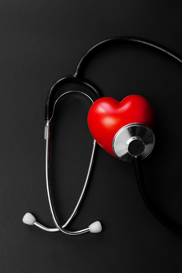 Cuore rosso e stetoscopio su carta nera. Elementi essenziali distesi per il medico che utilizzano il trattamento e la cura del paziente in ospedale.