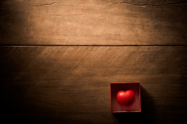 Cuore rosso in confezione regalo su tavola di legno.