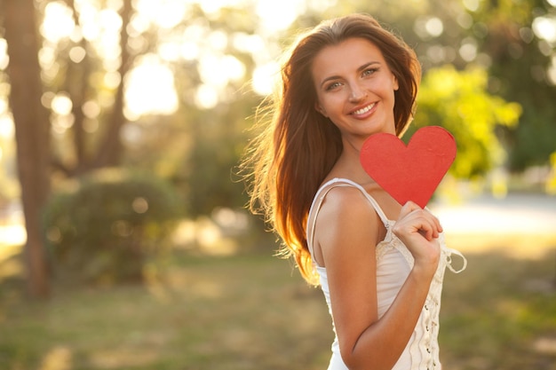 Cuore rosso nella mano destra di una bella donna. Avvicinamento