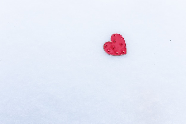 Cuore rosso si trova nella neve, concetto di vacanza di San Valentino, spazio per un'iscrizione.
