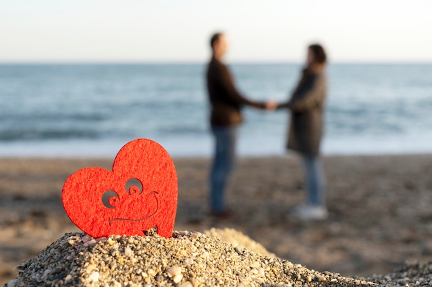 Cuore rosso su una montagna di sabbia sul mare con una coppia di amanti. concetto di san valentino