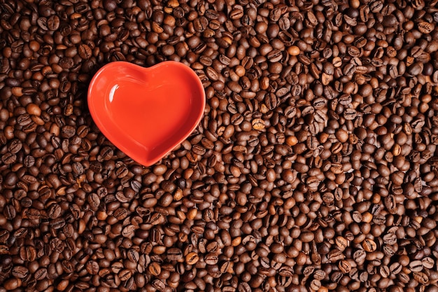 Cuore rosso su uno sfondo di chicchi di caffè simbolo di amore biglietto di auguri per san valentino buongiorno c...