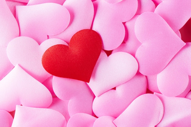 Cuore rosso sullo sfondo di molti cuori rosa. Il concetto di San Valentino, amore, tradimento, poligamia