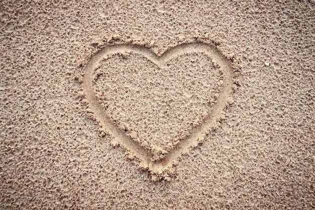 Cuore su una sabbia di spiaggia sullo sfondo