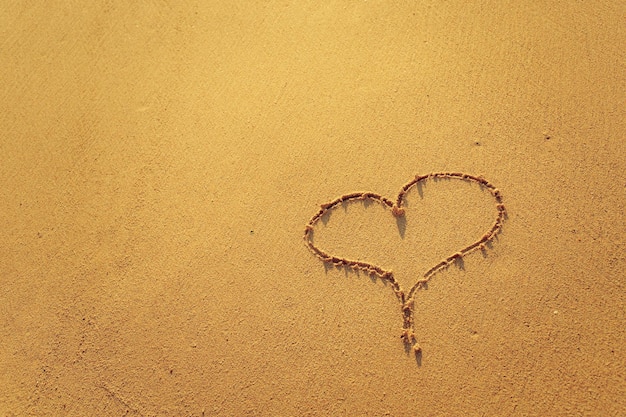 Cuore sulla spiaggia con il tramonto Copia spazio