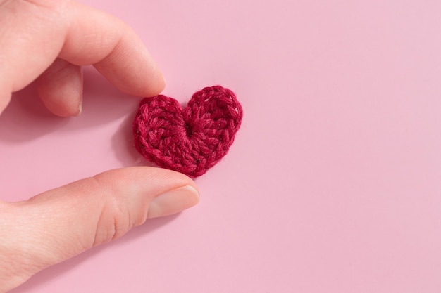 Cuore viola amigurumi all'uncinetto nella mano di una donna Stendardo di San Valentino