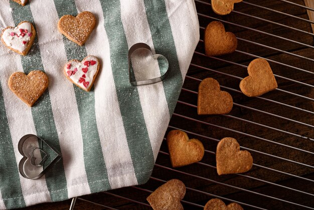 Cuori di biscotti sul tovagliolo di stoffa bianco e verde con cuori di forme metalliche su griglia metallica per San Valentino