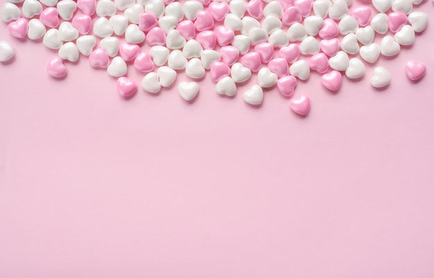 Cuori di caramelle su sfondo rosa per San Valentino. Copia spazio. Modello