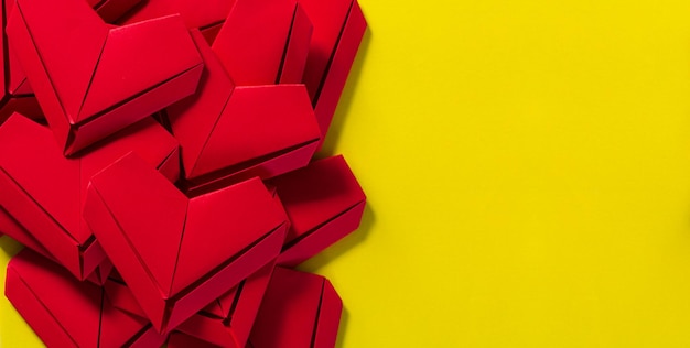 Cuori di carta su sfondo giallo il concetto di amore il giorno di San ValentinoOrigami rossi