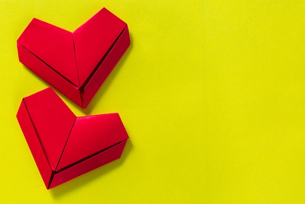 Cuori di carta su sfondo giallo il concetto di amore il giorno di San ValentinoOrigami rossi