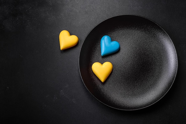 Cuori di cioccolato nei colori della bandiera ucraina su un piatto di ceramica nera