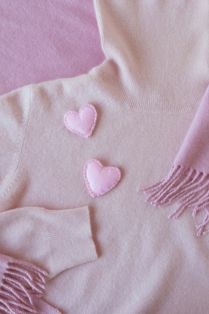 Cuori di feltro su vestiti di cashmere rosa vista dall'alto concetto di San Valentino prodotti caldi e accoglienti