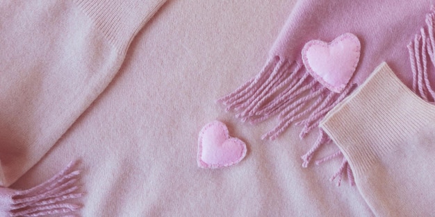 Cuori di lana carini decorano abiti in cashmere rosa vista dall'alto Concetto di San Valentino caldo e accogliente
