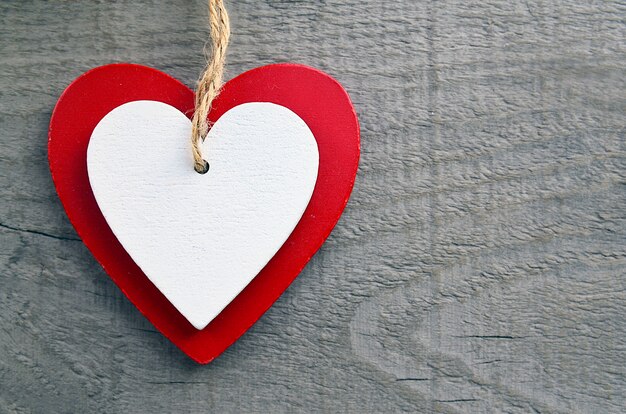 Cuori di legno rossi e bianchi decorativi su un fondo di legno grigio. San Valentino o concetto di amore.