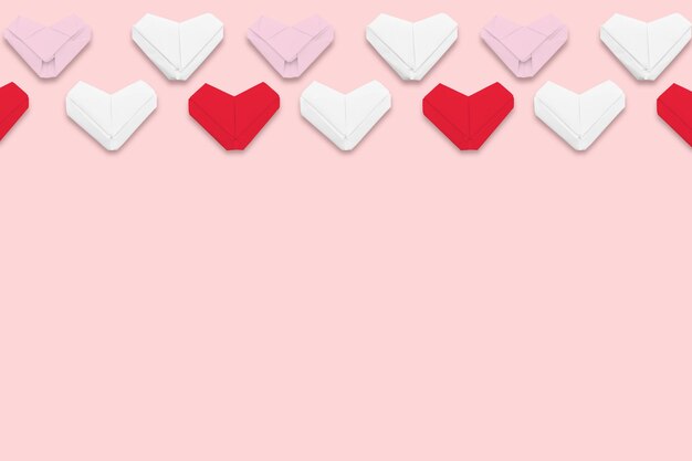 Cuori di origami di carta rossa e bianca su sfondo rosa Composizione per il Giorno di San Valentino