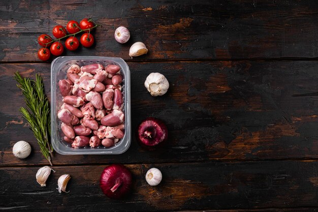 Cuori di pollo con carne fresca cruda in set di contenitori di plastica, su sfondo di un vecchio tavolo in legno scuro, vista dall'alto piatto, con spazio per la copia del testo