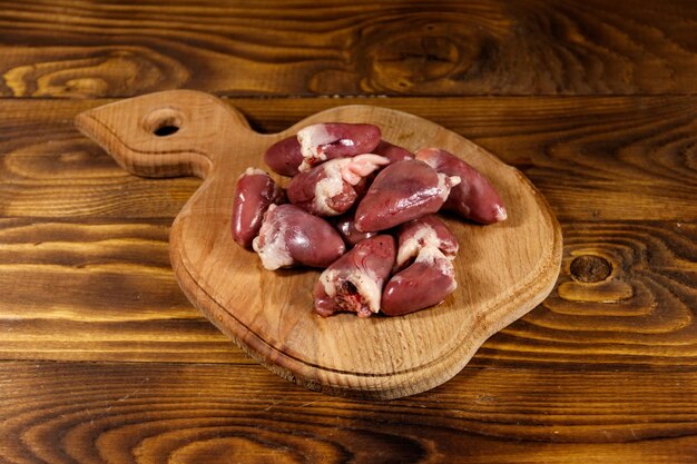 Cuori di pollo crudi sul tagliere sul tavolo di legno