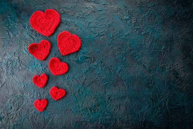 Cuori di San Valentino all'uncinetto rosso su sfondo scuro.