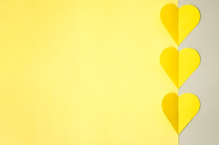 Cuori gialli ritagliati di carta colorata su sfondo grigio