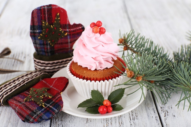 Cup-cake su piattino con decorazioni natalizie su tavolo in legno colorato