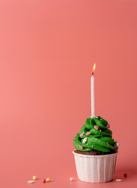 Cupcake a forma di albero di Natale con candela su sfondo rosa