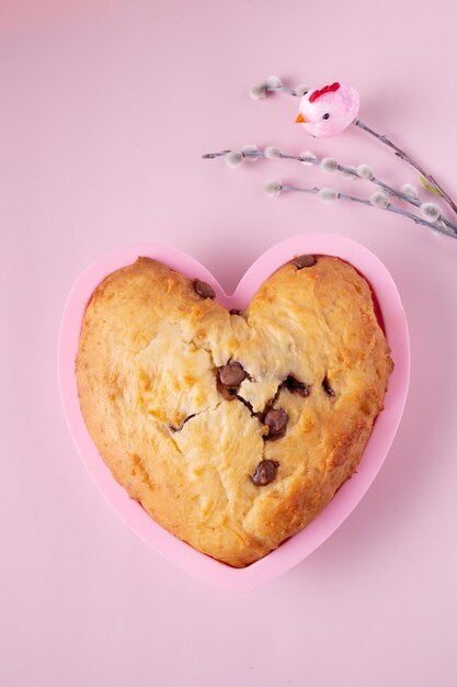 Cupcake a forma di cuore con pezzi di cioccolato e rami di salice su sfondo rosa primo piano