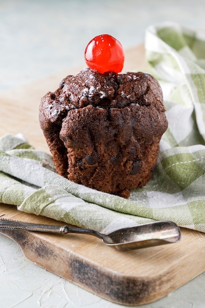 Cupcake al cioccolato con glassa sul tovagliolo su tavola di legno e vecchio cucchiaio