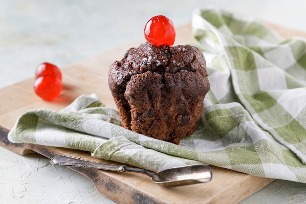 Cupcake al cioccolato con glassa sul tovagliolo su tavola di legno e vecchio cucchiaio