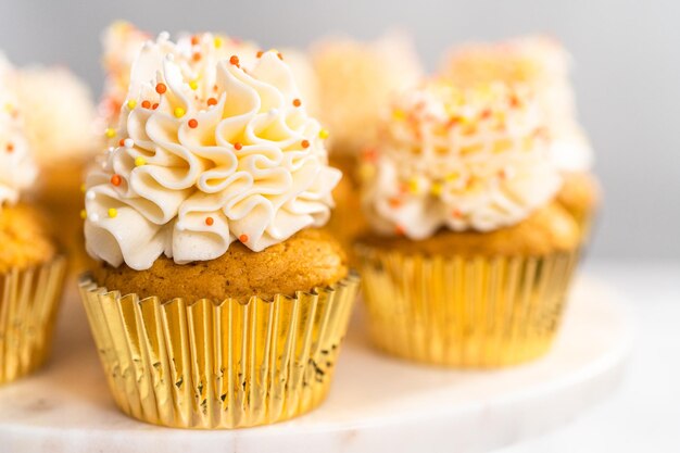 Cupcake alle spezie di zucca con crema al burro italiana e spruzza su un'alzatina.