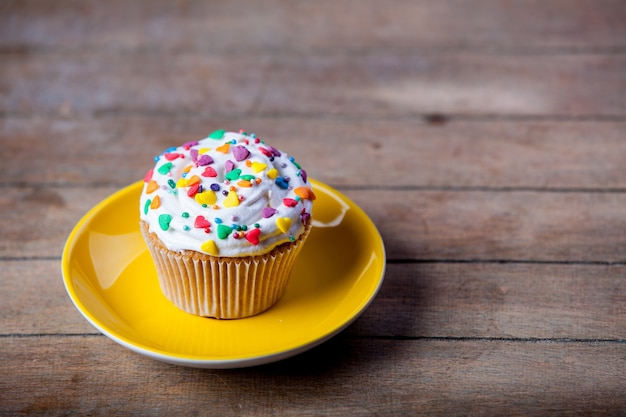 Cupcake colorati su un piatto e un tavolo in legno.