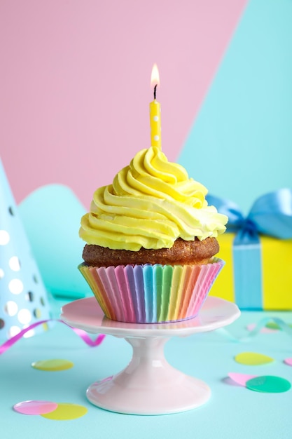 Cupcake compleanno delizioso con candela su sfondo colorato