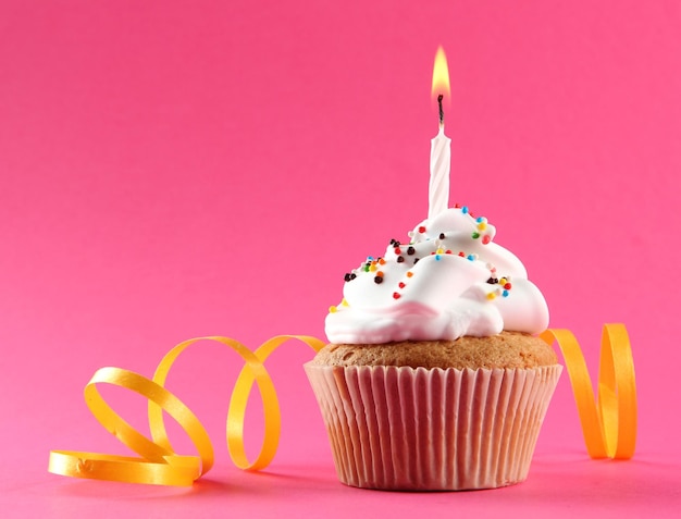Cupcake compleanno gustoso con candela su sfondo rosa