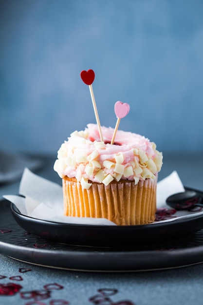 Cupcake con formaggio crema e fragole Cupcake per San Valentino su un tavolo di cemento