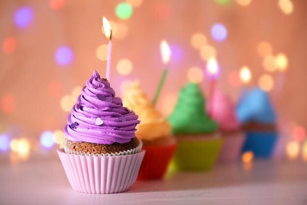 Cupcake con glassa crema viola e candela su uno sfondo glitter da vicino