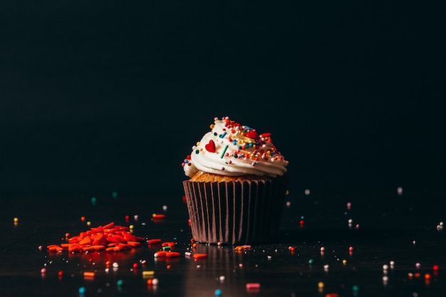 Cupcake cosparso di decorazioni sul nero