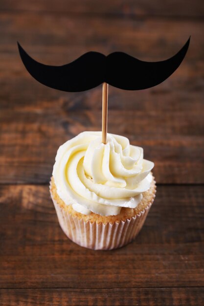 Cupcake creativo delizioso con i baffi sulla tavola di legno