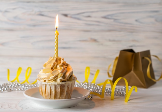 Cupcake di buon compleanno con candela accesa e un regalo