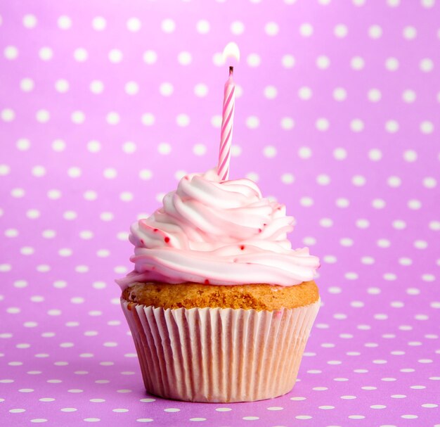 Cupcake di compleanno gustoso con candela su sfondo viola