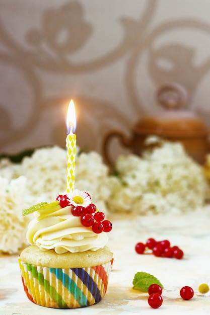 Cupcake festivo con panna e frutti di bosco e una candela