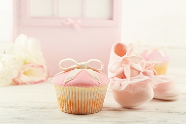 Cupcake gustoso con fiocco e scarpe per bambini carrozzina decorativa su sfondo colorato