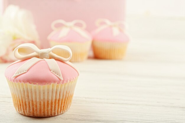 Cupcake gustoso con fiocco e scarpe per bambini, carrozzina decorativa su superficie colorata