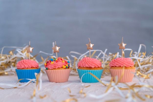 Cupcake natalizio decorato con glassa di crema al burro rosa e cuori. I muffin sono decorati con candele a forma di stella.