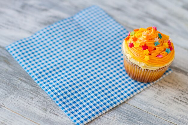 Cupcake su glassa di tovagliolo blu di colore arancione nuovo dessert nel menu dei bistrot cibo gustoso e buon servizio