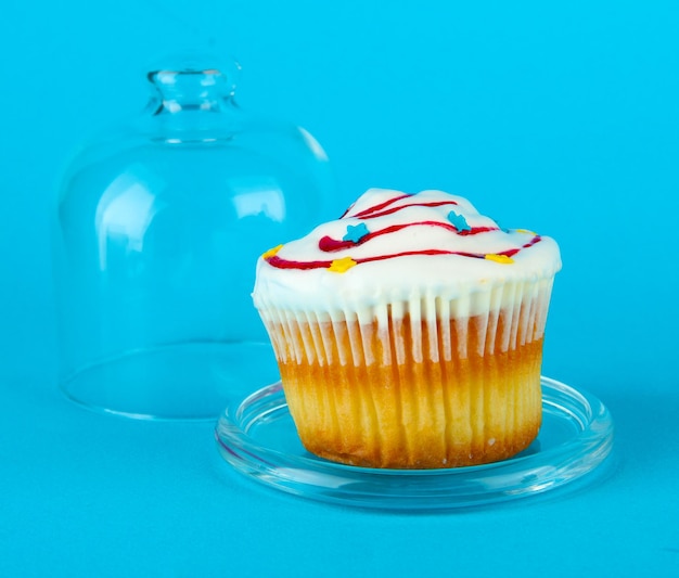 Cupcake su piattino con coperchio in vetro su sfondo colorato
