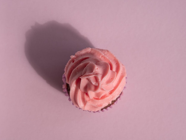 Cupcake su uno sfondo rosa con un cappuccio di crema dura ombra vista dall'alto